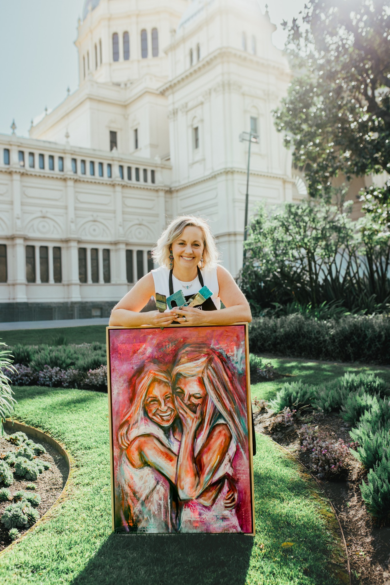 Artist Tracy Lee holding one of her paintings